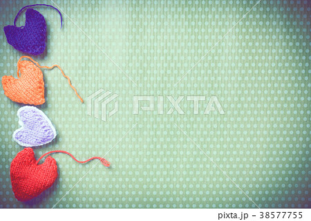 Colorful knitted hearts on a green background 38577755