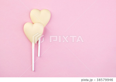 Two white chocolate candy hearts on pink Two white chocolate candy hearts on pink 38579946