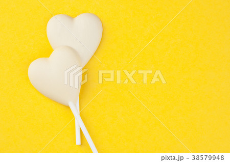 Two white chocolate candy hearts on yellow Two white chocolate candy hearts on yellow 38579948