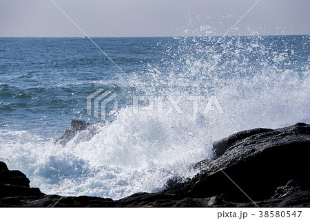 岩に打ち寄せる荒波　波しぶきイメージ 38580547