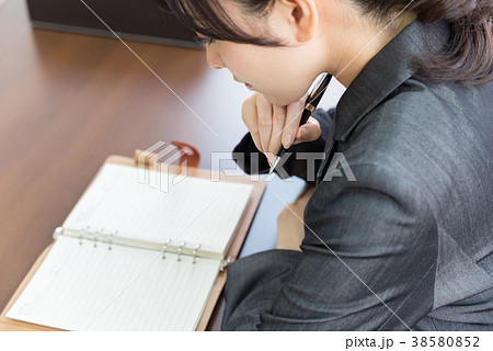 手帳に記入するスーツの女性 手帳に記入するスーツの女性 38580852