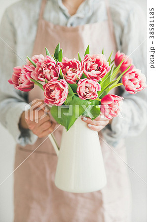 Woman holding white enamel vase with fresh pink Woman holding white enamel vase with fresh pink 38581185