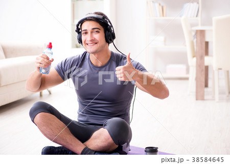 Man doing sports at home and listening to music Man doing sports at home and listening to music 38584645