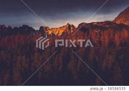 Last sun light hits high mountains peak at sunset Last sun light hits high mountains peak at sunset 38586535