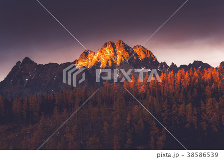 Last sun light hits high mountains peak at sunset 38586539