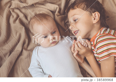 little boy playing with newborn on the bed 38589968