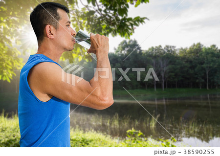 Man drinking water from glass on blurred nature Man drinking water from glass on blurred nature 38590255