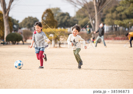 公園でサッカーをする子供の写真素材