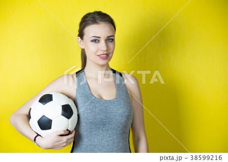 Girl with a soccer ball on a yellow background. 38599216