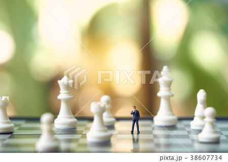 Miniature businessmen standing on a chessboard Miniature businessmen standing on a chessboard 38607734
