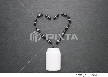 Black supplement capsules arranged in heart shape Black supplement capsules arranged in heart shape 38612660