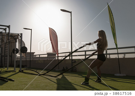 Sports woman doing battle ropes exercises in a 38617516
