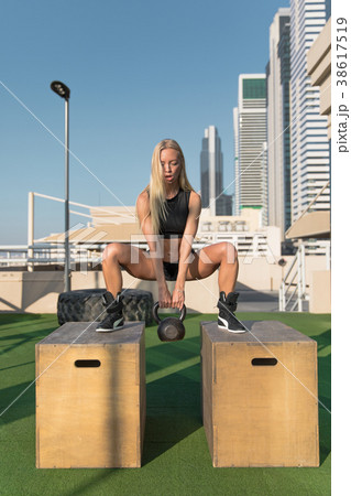Young woman doing squats with kettlebell at gym. Young woman doing squats with kettlebell at gym. 38617519