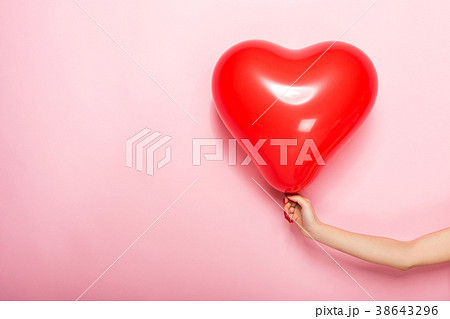Female hand holding a red ball in the shape of a 38643296