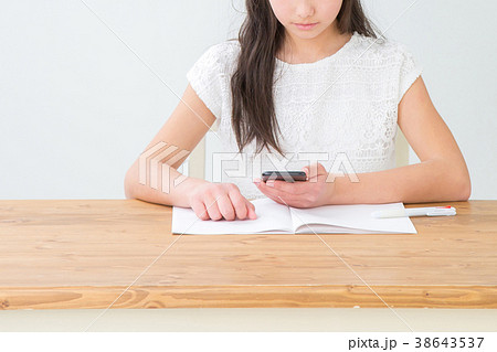 スマホを見ながら勉強する女の子 スマホを見ながら勉強する女の子 38643537