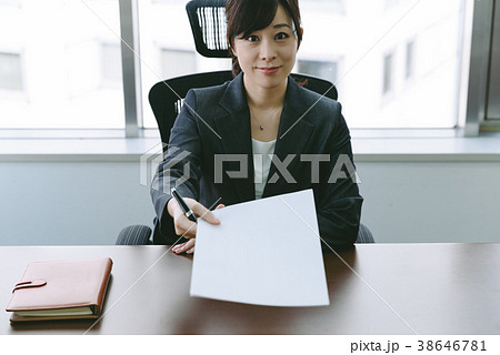 書類を渡すスーツの女性の写真素材