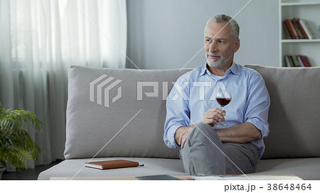 Happy adult person sitting on sofa, drinking red Happy adult person sitting on sofa, drinking red 38648464