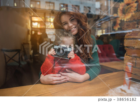 Cheerful daughter using photo camera near mother Cheerful daughter using photo camera near mother 38656182