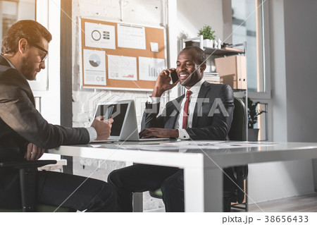 Cheerful stylish guys are using phone in office 38656433