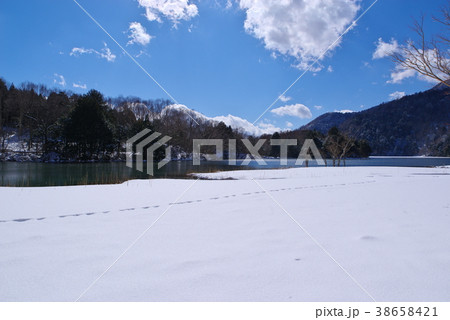 冬の奥日光 湯ノ湖 湖畔の雪の足跡と青い空　b 38658421