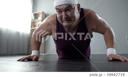 Motivated plump man in his 50s doing push-up with 38662738