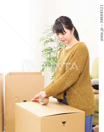 ダンボール箱をガムテープで閉じる女性 ダンボール箱をガムテープで閉じる女性 38668521