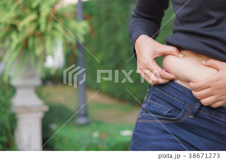 Chubby woman hand holding her own belly fat Chubby woman hand holding her own belly fat 38671273