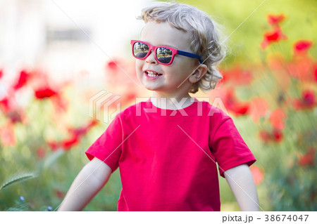 Pretty blond boy is wearing sunglasses holding red 38674047