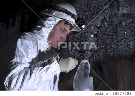 the cave explorer looks at the icy stalagmite 38677583