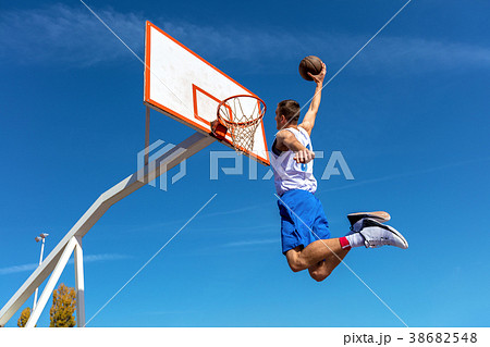 Young Basketball street player making slam dunk 38682548