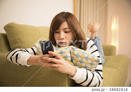 寝そべってスマホを見る女性 38682818