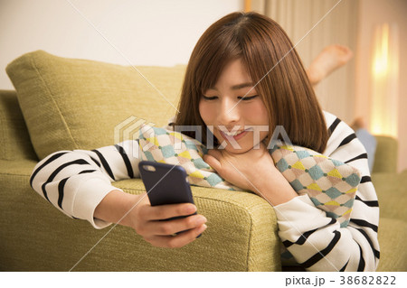 寝そべってスマホを見る女性 38682822