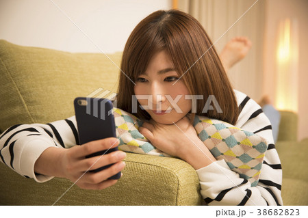 寝そべってスマホを見る女性 38682823
