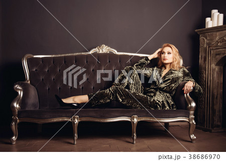 Beautiful woman on vintage couch near a fireplace Beautiful woman on vintage couch near a fireplace 38686970