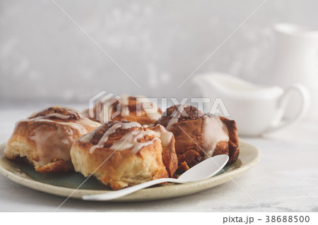 Homemade cinnamon buns in glaze on a light plate 38688500