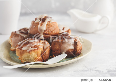 Homemade cinnamon buns in glaze on a light plate Homemade cinnamon buns in glaze on a light plate 38688501