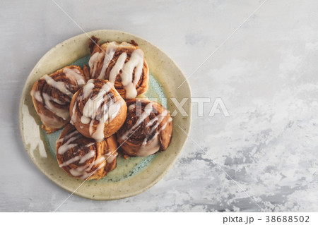 Homemade cinnamon buns in glaze on a light plate Homemade cinnamon buns in glaze on a light plate 38688502