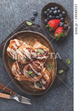 Homemade cinnamon buns in glaze on a dark plate Homemade cinnamon buns in glaze on a dark plate 38688507
