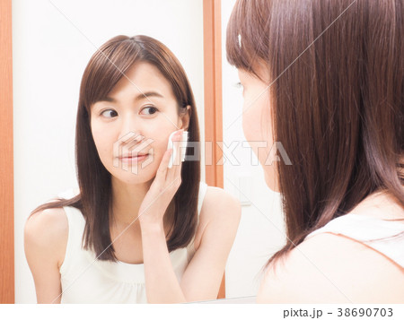 コットンを手にして鏡を見る女性 38690703