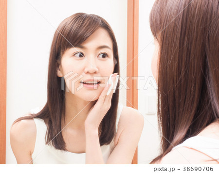 コットンを手にして鏡を見る女性 38690706
