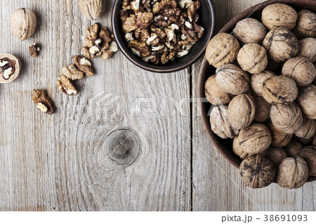 Walnut kernels in a  bowl and whole walnuts 38691093