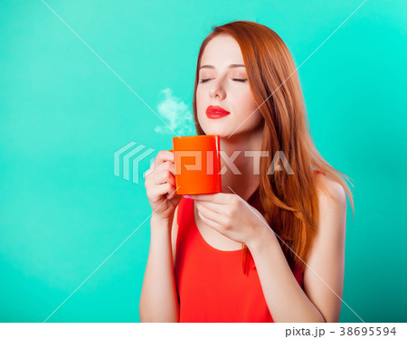 Redhead girl with coral cup of coffee or tea Redhead girl with coral cup of coffee or tea 38695594