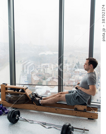 Man working out on row machine in fitness studio 38702374