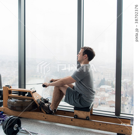 Man working out on row machine in fitness studio Man working out on row machine in fitness studio 38702376