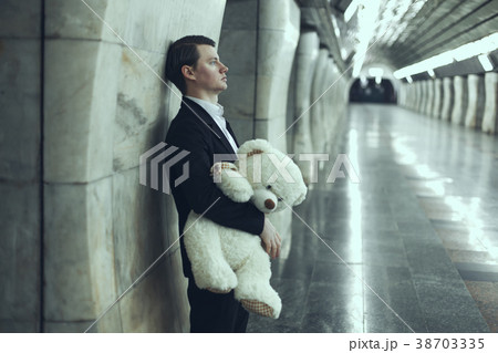 Man is sad with a teddy bear toy in his hands. 38703335