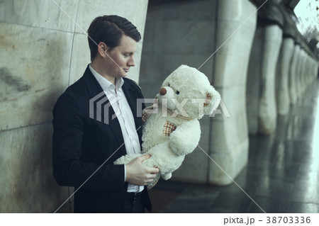 Guy smiles a big plush toy. 38703336