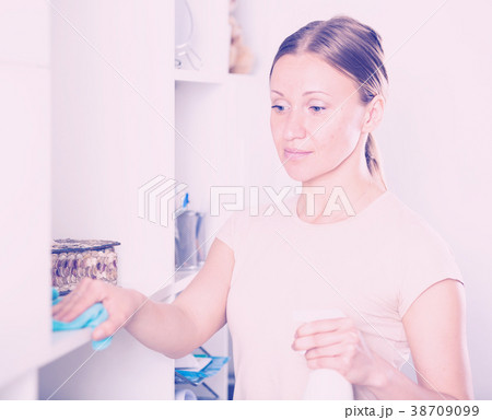 Smiling woman wiping shelves Smiling woman wiping shelves 38709099