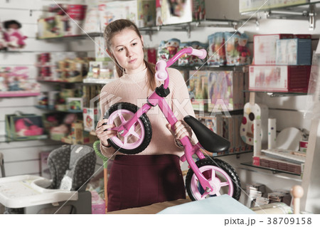 Young woman holding balance bicycle in the shop of goods for chi 38709158