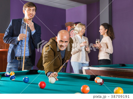 Group of cheerful friends playing billiards 38709191