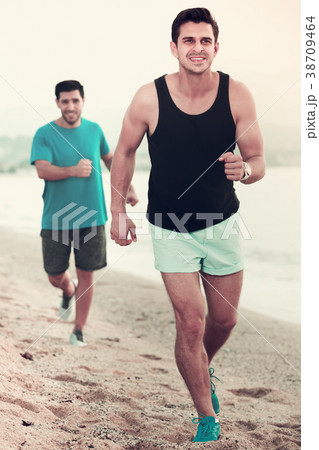 Two sportsmen jogging on beach 38709464
